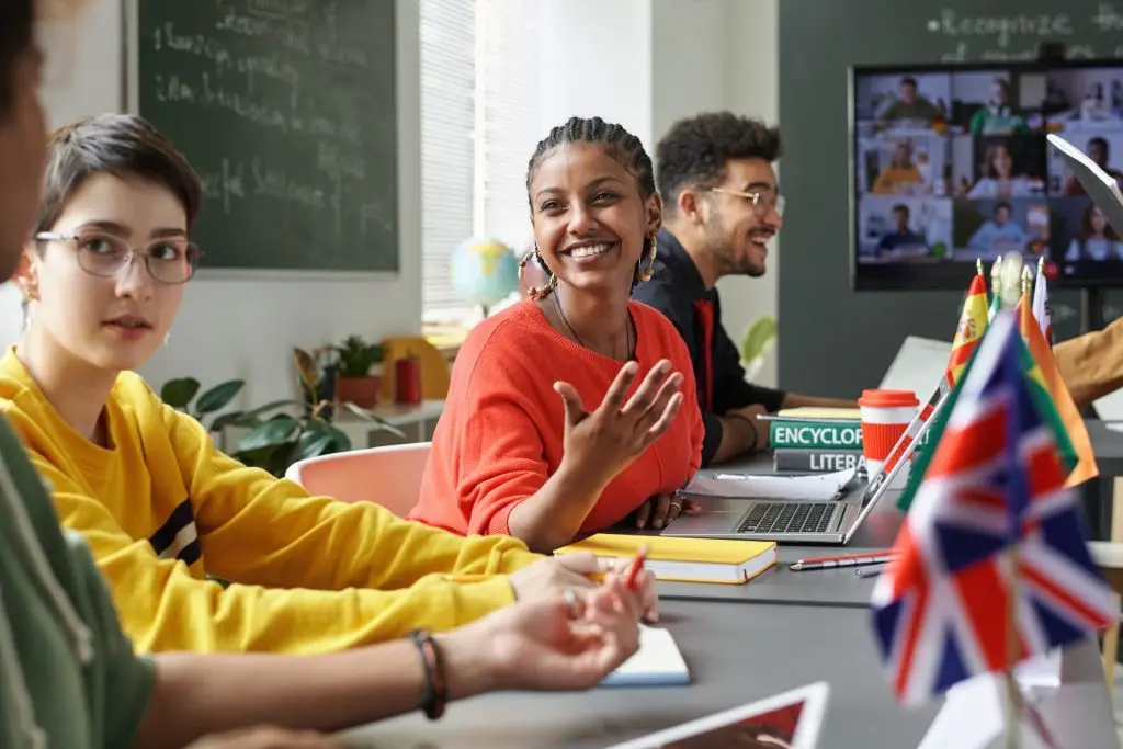 Students taking part in a classroom discussion, with a video call on the screen behind them