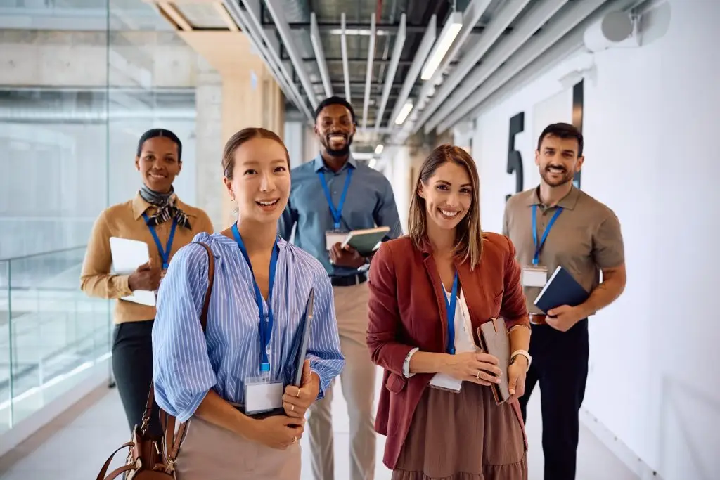 Five professionals wearing lanyards walking along an office corridor