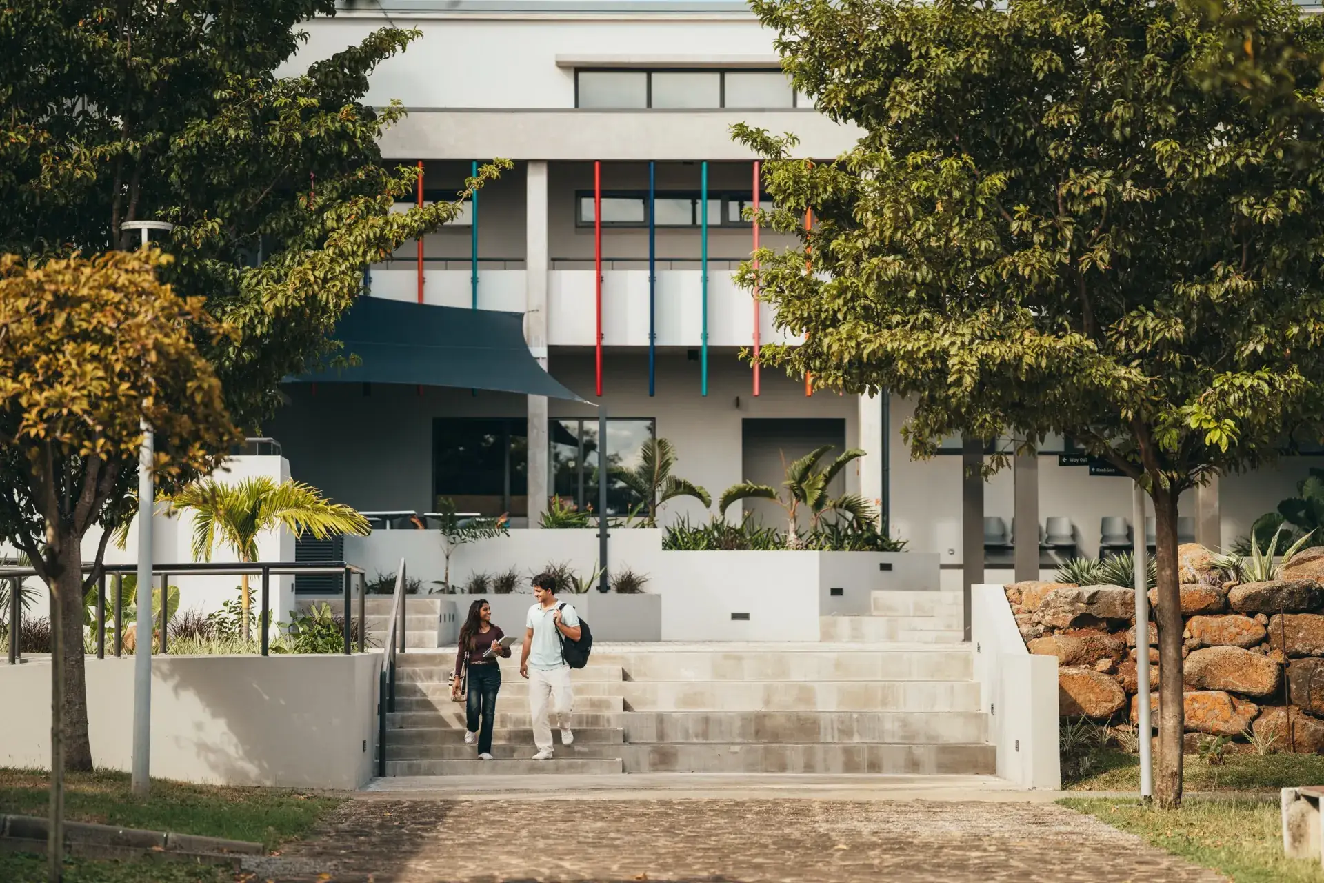 Two Middlesex University Mauritius students walking down the steps of the campus building