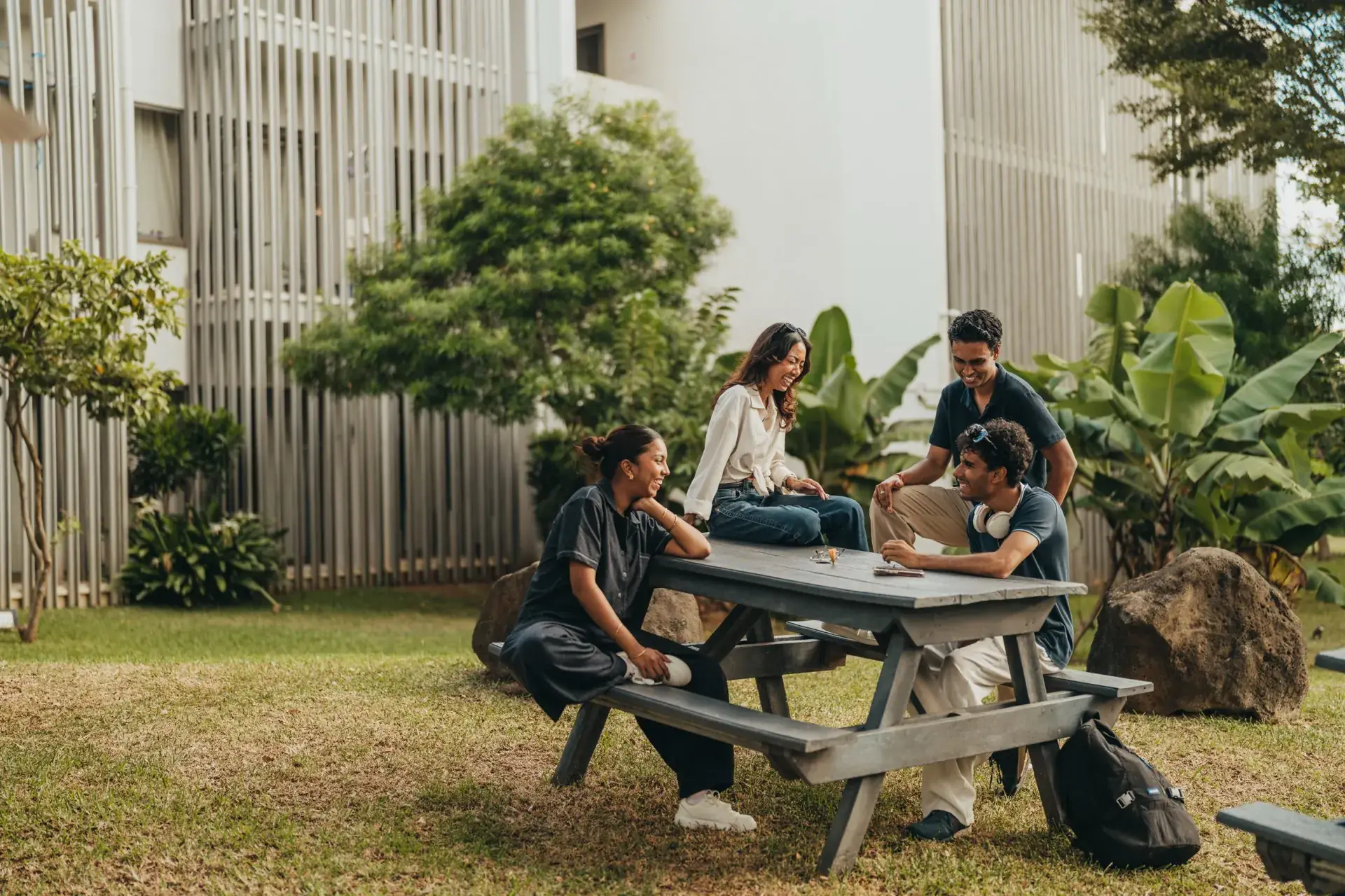 Four Middlesex University Mauritius students chatting around a picnic table on campus