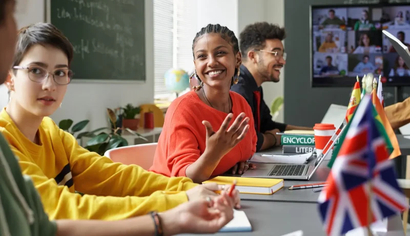 Students taking part in a classroom discussion, with a video call on the screen behind them