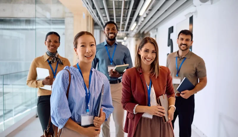 Five professionals wearing lanyards walking along an office corridor